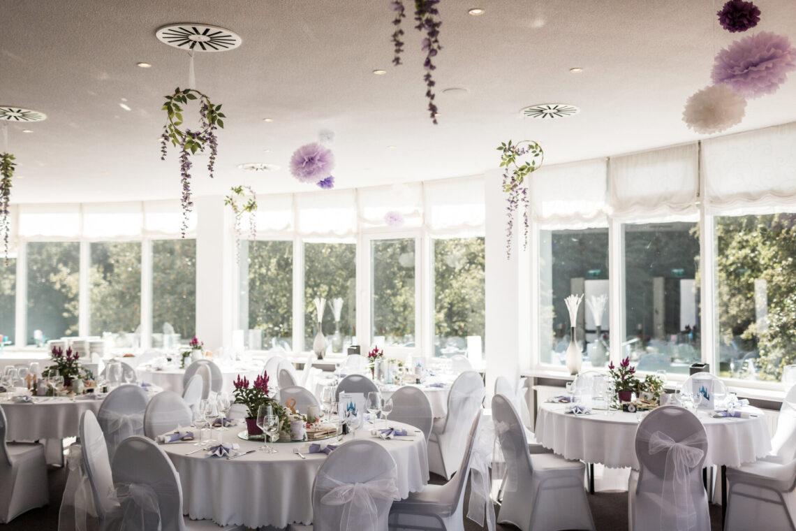 Saal dekoriert für eine Hochzeit mit hängenden Blumen und Hussen über den Stühlen