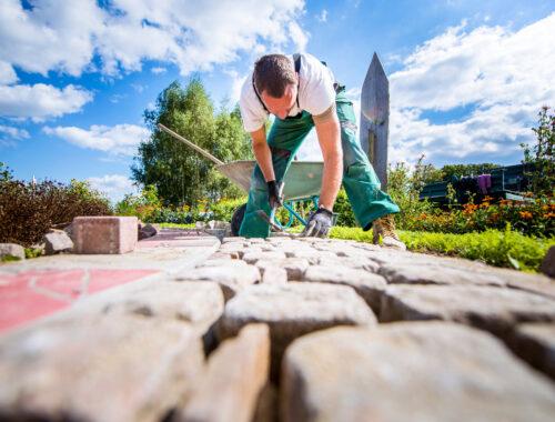 Handwerker verlegt Pflastersteine in einer Gartenanlage